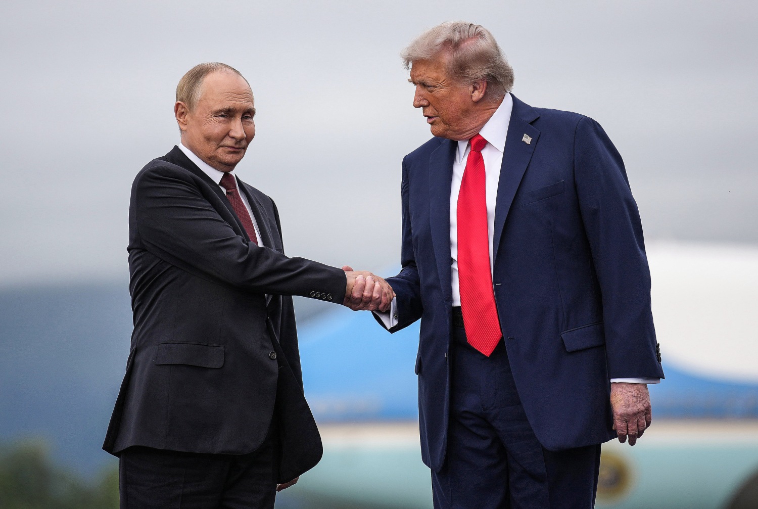Donald Trump og Vladimir Putin tar hverandre i henda. (Foto: Andrew Harnik/Getty.)