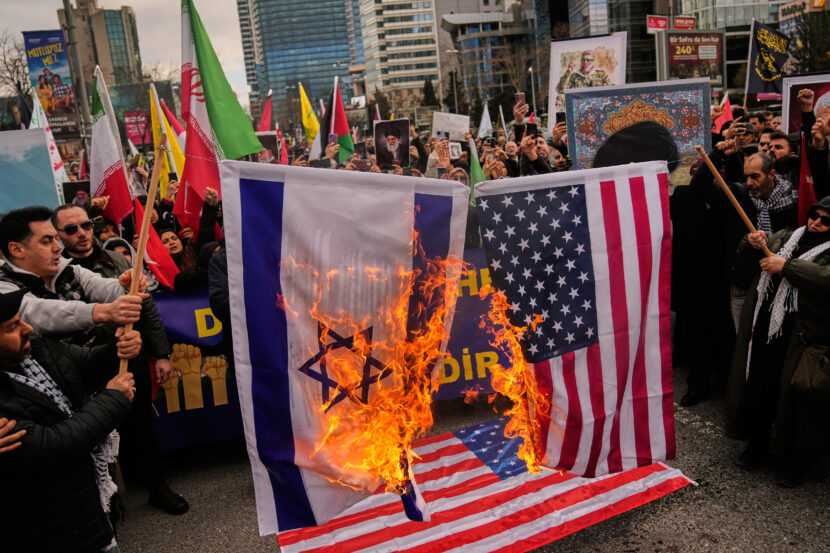 Demonstranter brenner et israelsk og et amerikansk flagg under en protest utenfor det israelske konsulatet i Istanbul, søndag 1. mars 2026. (Foto: AP / Khalil Hamra.)