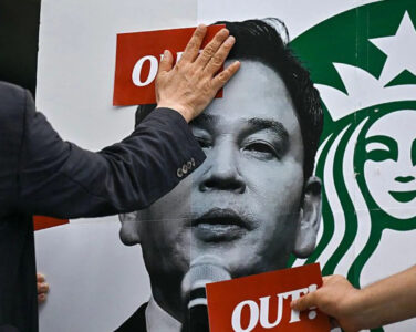 Demonstrantert trykker «OUT!»-klistremerker på en Starbucks-plakat. (Foto: AFP/Getty.)