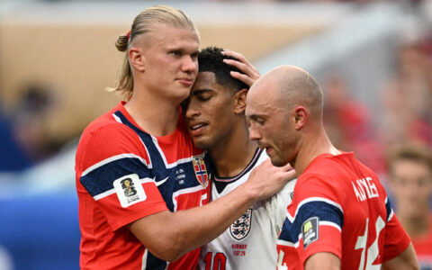 Erling Braut Haaland klemmer kameraten Jude Bellingham (England) etter kvartfinalen i VM 2026. Fredrik Aursnes (Norge) sørger stoisk i forgrunnen. (Foto: AFP.)