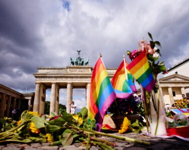 Flowers and rainbow flags placed in front of the Brandenburg Gate commemorating the victims of a car attack on Saturday's Pride March in Berlin, Germany, Monday, July 27, 2026. (Foto: AP/Markus Schreiber.)
