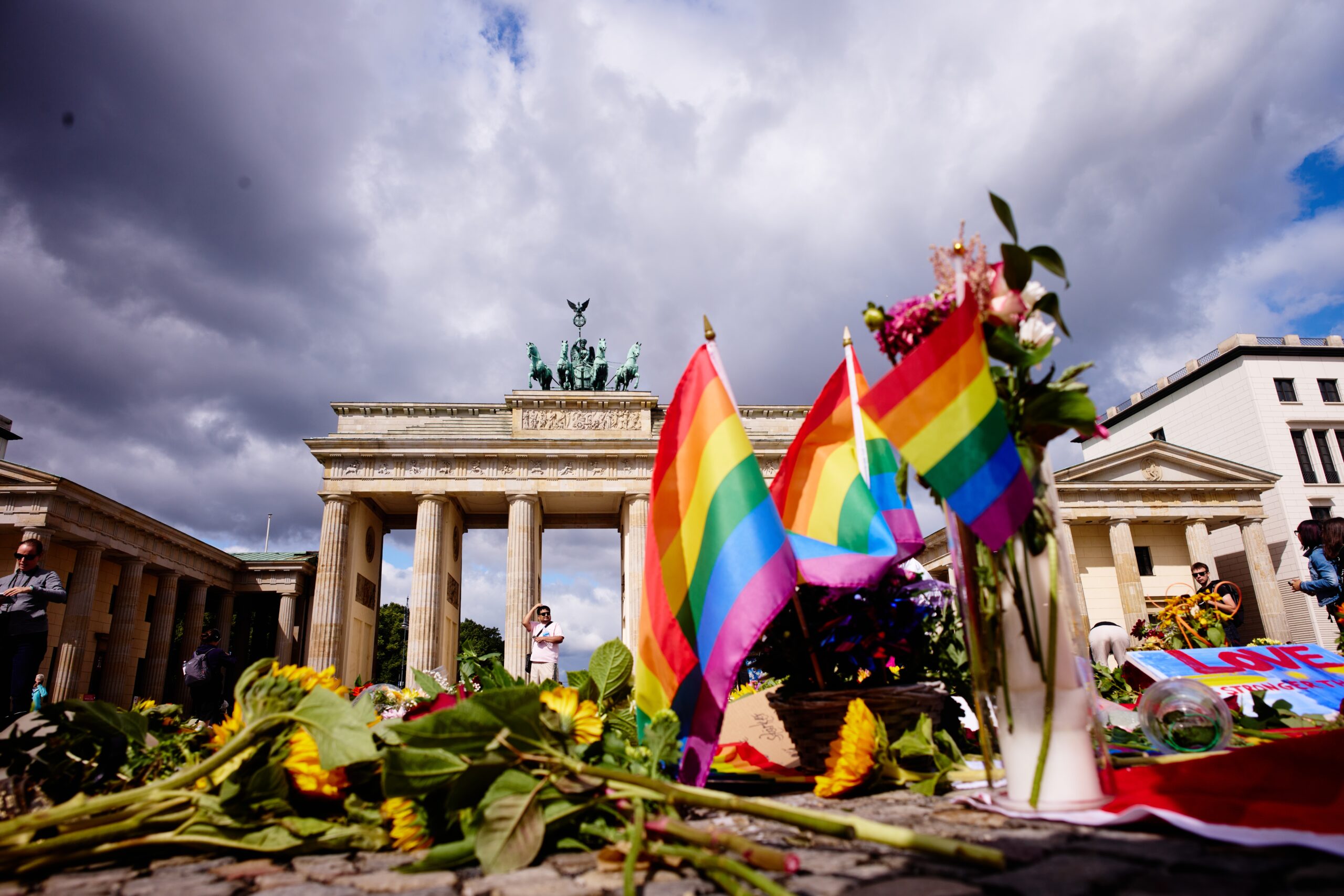 Flowers and rainbow flags placed in front of the Brandenburg Gate commemorating the victims of a car attack on Saturday's Pride March in Berlin, Germany, Monday, July 27, 2026. (Foto: AP/Markus Schreiber.)